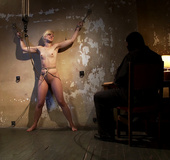 Tall long legged blond is held in a creepy room by masked man. She's bound